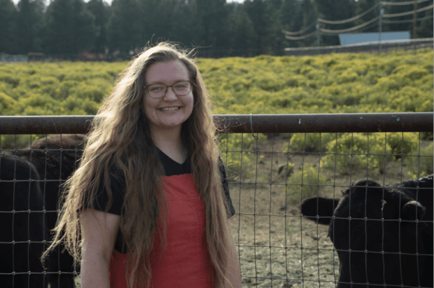Bailey Erwin standing next to cows